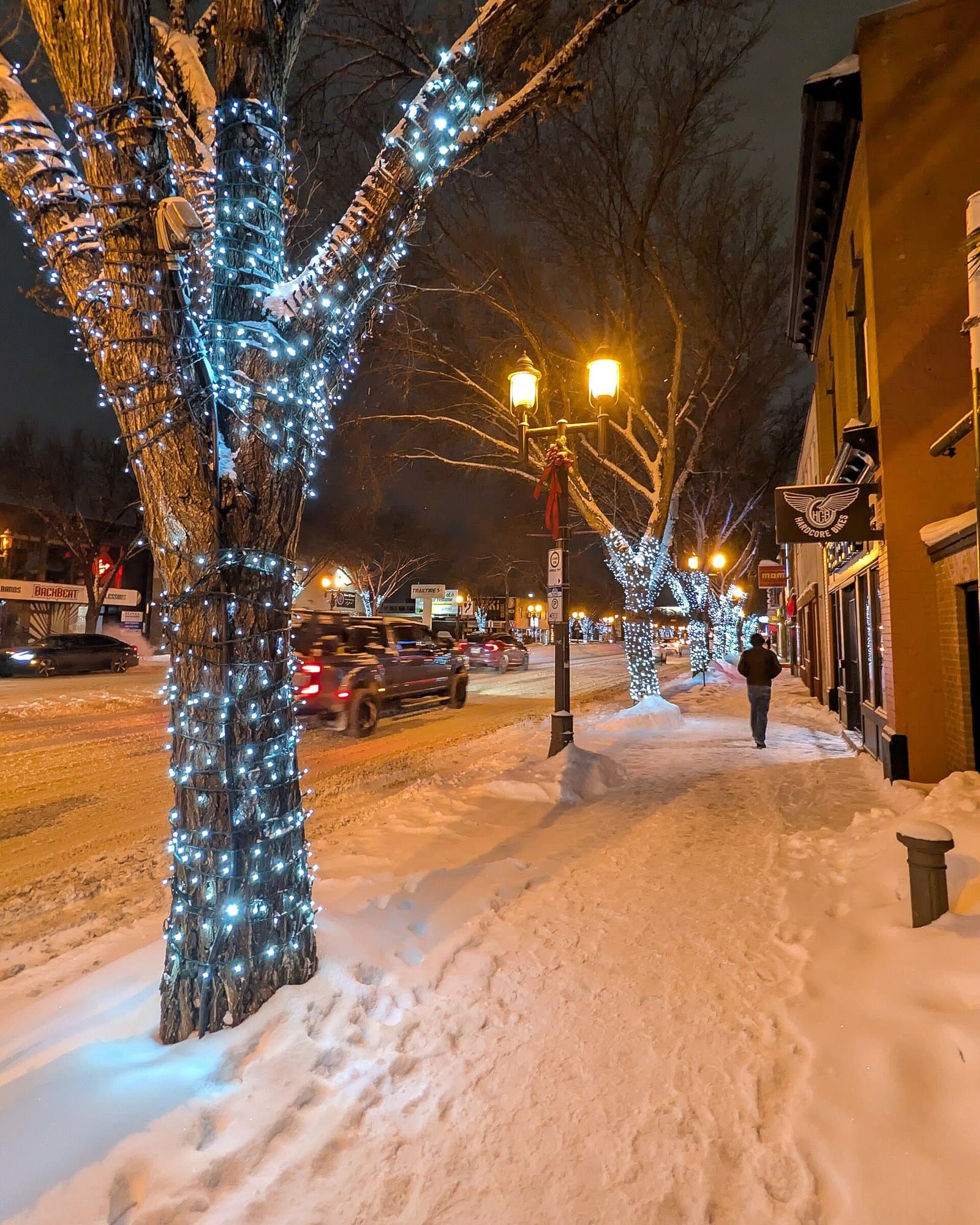 Whyte Avenue at night in Old Strathcona, Edmonton · brick storefronts, snowy sidewalk, and warm street lamps.